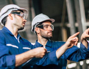 engineer teamwork checking control panel and teaching new worker to operating control the machine in factory.